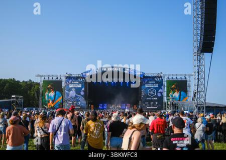 Scheeßel, Deutschland 20. Juni 2025: Hurricane Festival - 2025 im Bild: Das Bild zeigt eine große Menschenmenge vor der River Stage des Hurricane Festivals unter strahlend blauem Himmel. Im Zentrum des Fotos steht die beeindruckende Bühnenkonstruktion mit dem HURRICANE Logo und großen LED-Bildschirmen an beiden Seiten, die Live-Übertragungen des Konzerts zeigen. Die Festivalbesucher sind von hinten zu sehen, wie sie gespannt der Musik lauschen und die Festivalatmosphäre genießen. Ein großer Lautsprecher-Turm ist rechts im Bild erkennbar. Die Szene vermittelt die ausgelassene und energiegelade Stockfoto