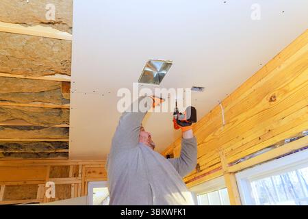 Der Auftragnehmer installiert Trockenbauwände an der Decke und arbeitet akribisch an Hausrenovierungsprojekten. Stockfoto