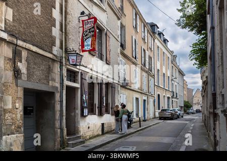 Das Restaurant Auberge Chez Cul de Paille liegt in einer Seitenstraße der Altstadt, Rue Théophraste Renaudot, Poitiers, Nouvelle-Aquitaine, Frankreich. Das Restaurant genießt in der Stadt Kultstatus. Der Speisesaal existiert in dieser Form seit 1843. Die Gäste wählen ihren eigenen Tischwein im Keller. Viele berühmte Künstler wie Jacques Brel, Georges Brassens und Charles Aznavour haben sich mit Autogrammen, Sprüchen und Zeichnungen an den Wänden verewigt. Ein rotes Schild mit der Aufschrift "Auberge Cul de Paille" hängt über dem Eingang. Zwei Frauen stehen vor der Anzeige am Eingang. Stockfoto