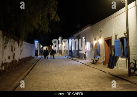 Touristen erkunden eine charmante Straße in San Pedro de Atacama bei Nacht. Stockfoto