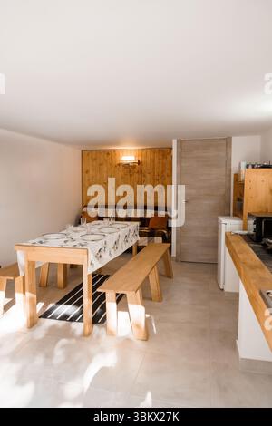 Der helle und einladende Speisesaal verfügt über eine hölzerne Wand, einen Tisch mit weißer Tischdecke und eine eingebaute Sitzbank, ideal für Familienessen Stockfoto
