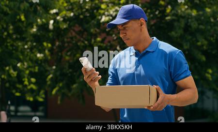 Kleinunternehmen Konzept afroamerikanischer Kurier Mann sucht Adresse mit Handy-App zu Fuß in der Stadt Zustellungsmann männliche Post Service E-Commerce Stockfoto