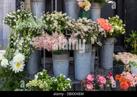Ein weitläufiges und farbenfrohes Blumengeschäft im Freien bietet eine große Auswahl an blühenden Blumen und Pflanzen in verzinkten Metalleimern und Töpfen. Stockfoto