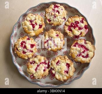 Blick von oben auf hausgemachte Beerenmuffins in einer Blumenschale auf einem rustikalen Holztisch. Stockfoto