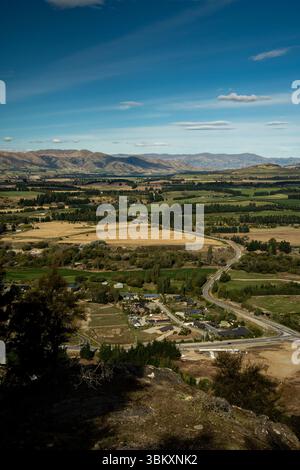 Ein landschaftlich reizvoller Blick auf eine ländliche Stadt zwischen sanften Hügeln und Feldern, die Natur und Wohnkultur miteinander verbindet. Verwinkelte Straßen, Wälder und ferne Berge Stockfoto
