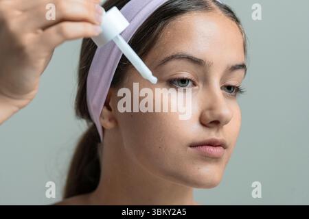 Eine Nahaufnahme einer jungen Frau, die ein feuchtigkeitsspendendes Gesichtsserum mit einem Tropfer aufträgt. Konzept einer täglichen Hautpflegeroutine und Schönheitsbehandlung Stockfoto