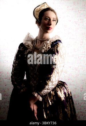In einem Atelierporträt wird eine Frau in einem historischen Kostüm, möglicherweise aus der Renaissance, dargestellt. Sie trägt ein raffiniertes Kleid mit einem High Stockfoto