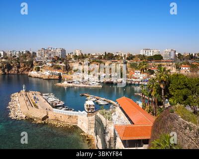 Ein Hochwinkelfoto fängt den malerischen Hafen von Antalya in der Türkei ein und zeigt eine lebhafte Mischung aus Booten, Gebäuden und natürlicher Schönheit unter einem klaren blauen Himmel. Das Bild unterstreicht den Charme der Stadt an der Küste und ihren Reiz als Touristenziel. Stockfoto