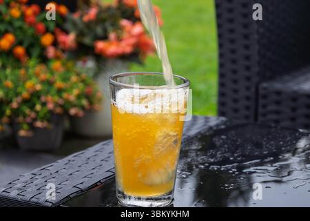 Voll gerahmtes Foto von einem Bier, das in ein Glas gießt. Eine schnellere Verschlusszeit zeigt Bewegungen in der Aufnahme an Stockfoto