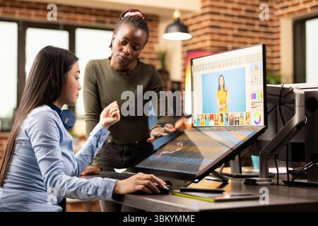 Multiethnische Designer arbeiten im Studio an Fotoretuschierungen zusammen und verfeinern Bilder für ein Projekt. In kreativen Arbeitsbereichen wählen verschiedene Frauen sorgfältig Bilder aus, die für eine Werbekampagne geeignet sind. Stockfoto