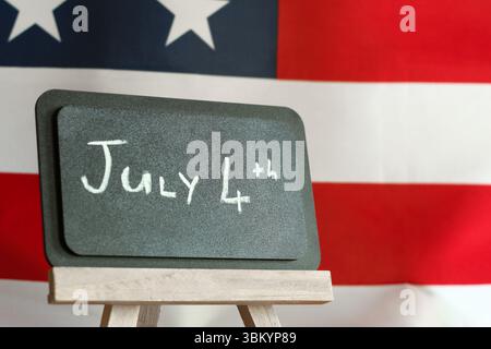 „4. Juli“ Botschaft auf der Tafel mit amerikanischem Flaggenhintergrund – Unabhängigkeitstag Celebration Concept Stockfoto