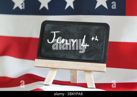 „4. Juli“ Botschaft auf der Tafel mit amerikanischem Flaggenhintergrund – Unabhängigkeitstag Celebration Concept Stockfoto