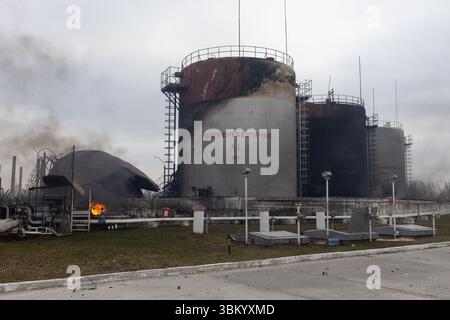 Mehrere große Kraftstofflagertanks weisen Anzeichen für einen erheblichen Schaden auf, wobei ein Tank einstürzte und sich entzündet und Rauch austritt. Krieg in der Ukraine, 2022. Stockfoto