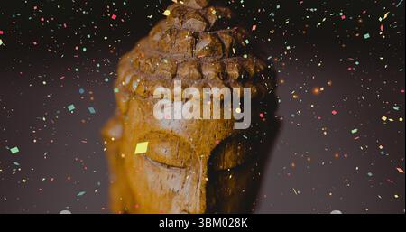 Geschnitzte hölzerne Buddha-Kopf-Statue im Studio, mit buntem Konfetti, das herumschwebt Stockfoto
