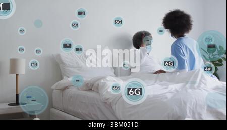 Liegender Patient, der von der Pflegekraft in einem Peeling auf dem Bett im Schlafzimmer versorgt wird, mit 6G-Symbolen Stockfoto