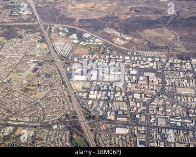 Diese Luftaufnahme erfasst die städtische Landschaft einer Stadt und zeigt eine Mischung aus Wohngebieten, Gewerbegebäuden und Industriezonen, die alle durch ein Netz von Autobahnen und Straßen miteinander verbunden sind, und hebt die Infrastruktur und Entwicklung der Stadt hervor. Stockfoto