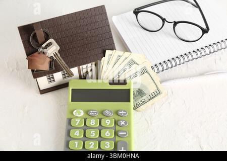 Hausmodell, Schlüssel, Geld und Taschenrechner auf weißem Tisch Stockfoto