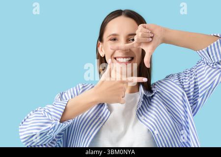 Junge Frau zeigt ihr wunderschönes Lächeln auf blauem Hintergrund Stockfoto