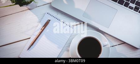 Laptop mit Buch und Kaffeetasse auf dem Tisch Stockfoto