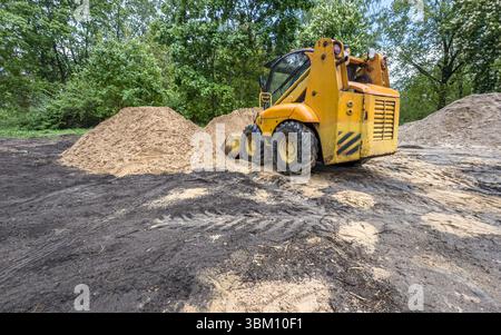 Kompaktlader-Bagger bei Bauarbeiten. Minilader bewegt die Erde auf der Baustelle. Stockfoto