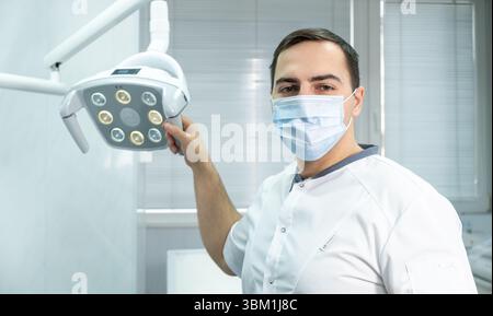 Professioneller Zahnarzt in Maske neben dem Zahnarztstuhl in der Zahnarztpraxis Stockfoto