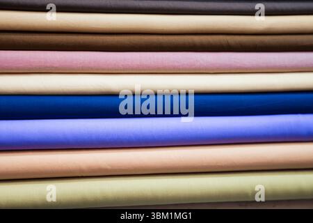 Eine Nahaufnahme zeigt einen sorgfältig angeordneten Stapel von Stoffrollen, die eine vielfältige Palette an Farben und Texturen zeigen. Jede Rolle zeigt ein Uniq an Stockfoto