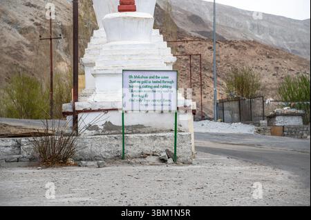 Malerische Straßenkreuzung in Ladakh mit inspirierendem Schild mit Buddha-Zitat vor Bergkulisse Stockfoto