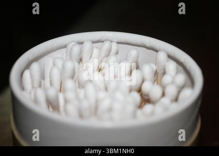 Dieses Bild zeigt eine detaillierte Nahaufnahme einer Gruppe von Wattestäbchen, die ordentlich in einem runden Behälter verpackt sind. Die Tupfer haben weiche, weiße Baumwollspitzen. Stockfoto