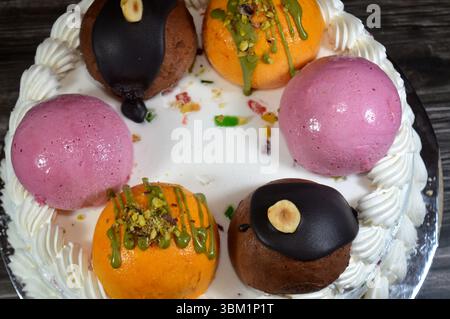 Eiskuchen Cassata, Vanille, Schlagsahne, Milch, gefüllt mit getrockneten Früchten, garniert mit Mangobällchen mit Pistazien und Sauce, Schokoladenkugel Stockfoto