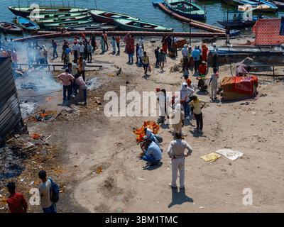 Indien, Varanasi, 16. März 2025. Pilger baden im heiligen Ganges neben Reihen von Holzbooten und farbenfrohen Fähren, die früh an den Ghats ankerten Stockfoto