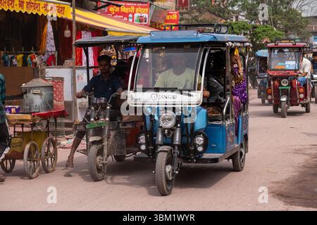 Indien, Jaipur, 14. März 2025. Blaue elektrische Rikscha (E-Rikscha), die Passagiere während des Holi Festivals, dem traditionellen indischen Markt in, auf belebten Straßen befördert Stockfoto
