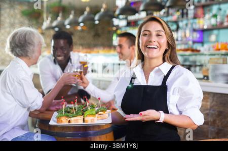 Blick auf die hispanische junge Dame, die Tapas hält Stockfoto