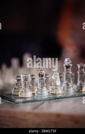 Detaillierte Ansicht von transparenten Glasschachfiguren, die auf einer Glasplatte angeordnet sind, mit sanfter Hintergrundunschärfe und natürlichem Licht. Stockfoto