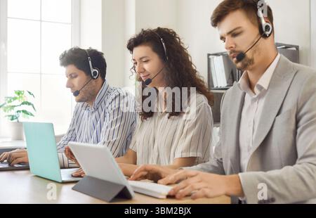 Junge Geschäftsleute, die in einer Reihe im Callcenter im Online-Support-Service-Büro arbeiten. Stockfoto