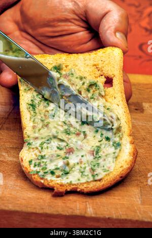 Nahaufnahme der Hände des Küchenchefs, die eine cremige Thunfisch- und Petersiliensauce auf ein Stück geröstetes Brot verteilen, wodurch eine köstliche Vorspeise oder ein Snack entsteht Stockfoto