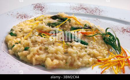 Cremiges Risotto mit zartem Spargel, pikanter Zitrone und aromatischem Estragon, wunderschön auf einem weißen Teller angeordnet, unterstreicht ein herrliches Flav Stockfoto