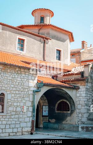 Altes Kirchengebäude mit Steinmauern, roten Dachziegeln und bogenförmigem Eingang an sonnigen Tagen. Stadt Omisalj, Insel Krk, Kroatien. Stockfoto