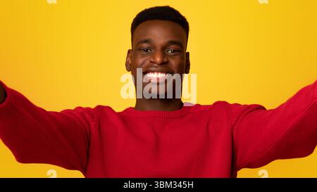 Selfie-Zeit. Fröhlicher junger afroamerikanischer Kerl, der Selbstporträt macht und lächelt Stockfoto