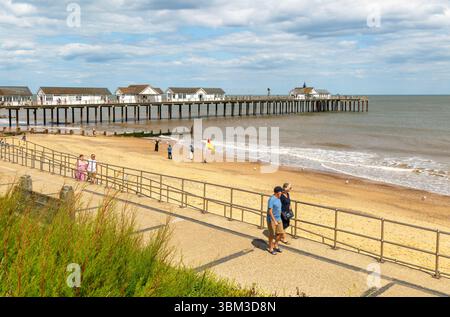 Menschen gehen auf der Strandpromenade neben Sandstrand und Pier, Southwold, Suffolk, England, Großbritannien Stockfoto