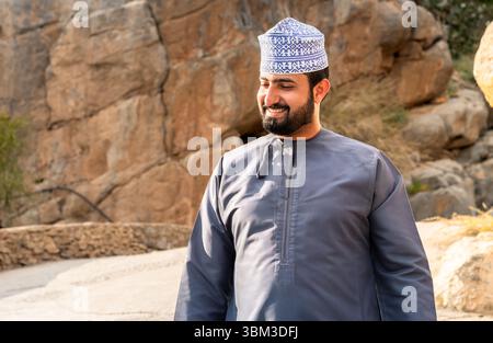 Misfat Al Abriyeen, Oman - 11. Februar 2020: Porträt eines lächelnden omanischen Mannes in traditionellem blauem Dschadscha und besticktem omanischen Kuma. Stockfoto