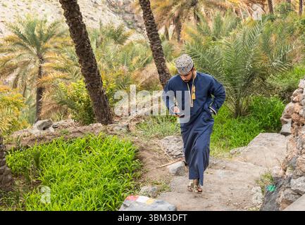 Misfat Al Abriyeen, Oman - 11. Februar 2020: Porträt eines lächelnden omanischen Mannes in traditionellem blauem Dschadscha und besticktem omanischen Kuma. Stockfoto