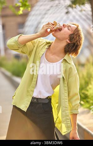 Goldener Moment. Junger Mann genießt Eis im Freien in urbaner Umgebung an sonnigen Tagen Stockfoto