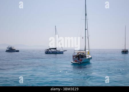 Mehrere Boote segeln auf dem ruhigen, offenen blauen Meer unter einem klaren Himmel Stockfoto