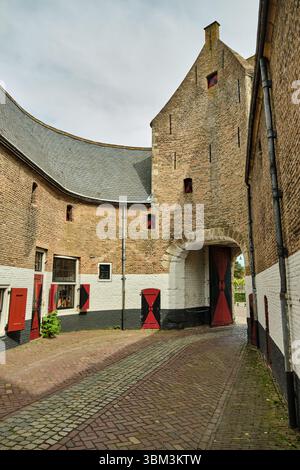 26. Mai 2025 - Zierikzee-Niederlande: Blick durch den Steinbogen des Noorderhavenpoorts, der eine Kopfsteinpflasterstraße, Backsteinmauern und eine Tradition enthüllt Stockfoto