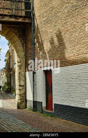 26. Mai 2025 - Zierikzee-Niederlande: Blick durch den Steinbogen des Noorderhavenpoorts, der eine Kopfsteinpflasterstraße, Backsteinmauern und eine Tradition enthüllt Stockfoto