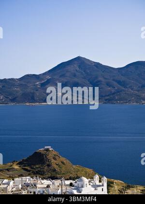 Panoramablick auf das Dorf Plaka auf der Insel Milos mit weißen kykladischen Häusern, Meer und grüner Bergkulisse. Stockfoto