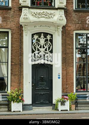 26. Mai 2025 - Zierikzee-Niederlande: Historisches Stadthaus de Aveling mit verzierten schwarzen Türen, großen Fenstern und bunten Blumenkästen vor einem Stockfoto