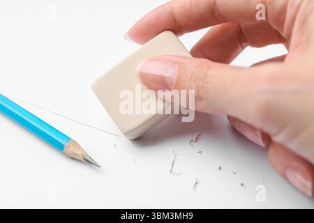 Frau benutzt Radiergummi auf weißem Papier, Nahaufnahme Stockfoto