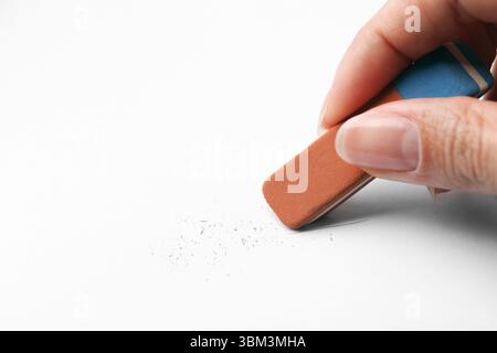 Frau benutzt Radiergummi auf weißem Papier, Nahaufnahme. Leerzeichen für Text Stockfoto