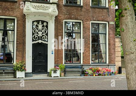 26. Mai 2025 - Zierikzee-Niederlande: Historisches Stadthaus de Aveling mit verzierten schwarzen Türen, großen Fenstern und bunten Blumenkästen vor einem Stockfoto